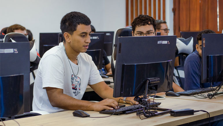 Estudiantes participando en una clase con Docencia con Tecnología Incorporada (DTI) en UNICIENCIA, utilizando computadoras y dispositivos digitales